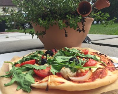 Ruccolapizza mit Cocktailtomaten, Oliven und gelber Zucchini